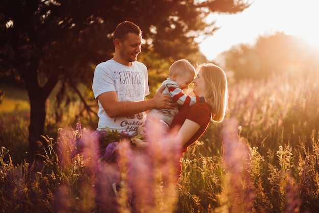 Le coppie felici della famiglia con il piccolo figlio posano sul campo di lavander