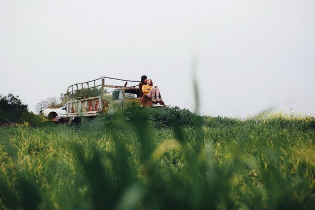 Le coppie nell'amore si siedono sul camion abbandonato e sorridono