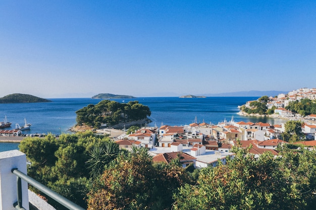 Le costruzioni bianche e marroni si avvicinano al mare circondato dagli alberi e dalle piccole isole a Skiathos, Grecia