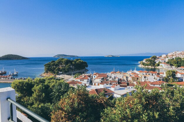 Le costruzioni bianche e marroni si avvicinano al mare circondato dagli alberi e dalle piccole isole a Skiathos, Grecia