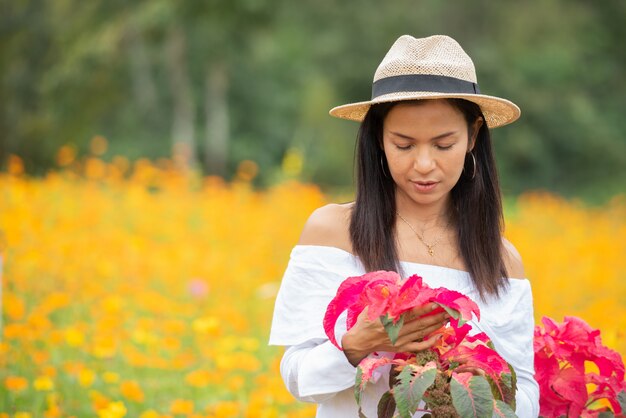 Le donne asiatiche stanno godendo i fiori rossi nel parco.