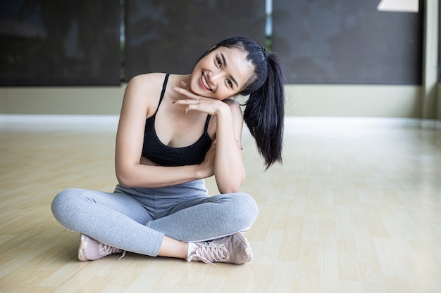 Le donne che si siedono indossando abiti e mento sulle loro mani stanno sorridendo.