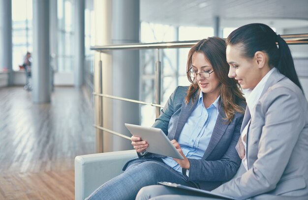 Le donne con tablet seduto sul divano