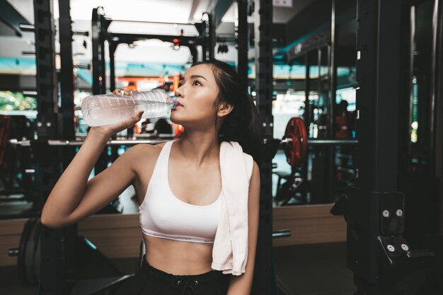 Le donne dopo l'esercizio bevono acqua da bottiglie e fazzoletti in palestra.