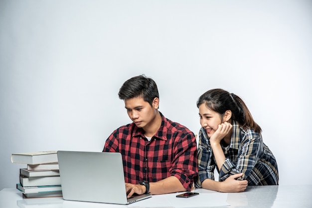 Le donne insegnano agli uomini come lavorare con i laptop al lavoro.