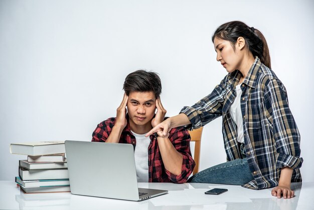 Le donne insegnano agli uomini come lavorare con i laptop al lavoro.