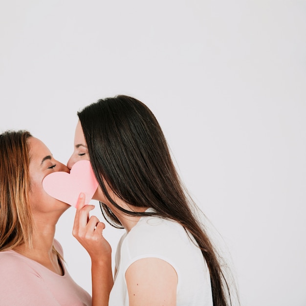 Le donne si accoppiano baciando e tenendo il cuore