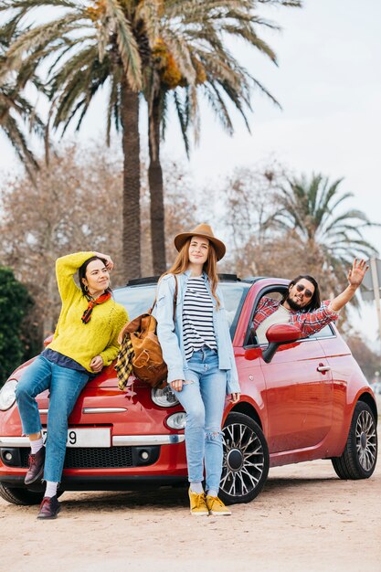 Le donne si avvicinano all&#39;uomo con la mano alzata sporgendosi dall&#39;auto