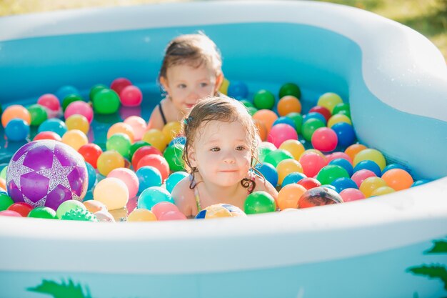 Le due bambine che giocano con i giocattoli in piscina gonfiabile nella giornata di sole estivo