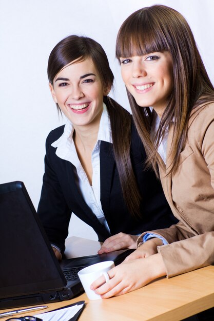 Le femmine sorridenti mentre si lavora su computer portatile