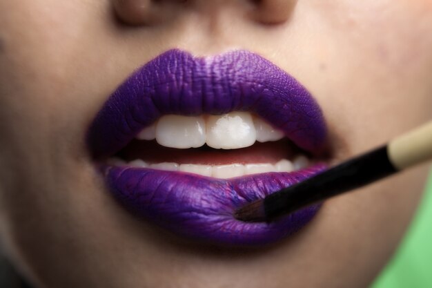 Le labbra di modelli femminili asiatici che indossano labbra viola si attaccano e ha denti bianco perla