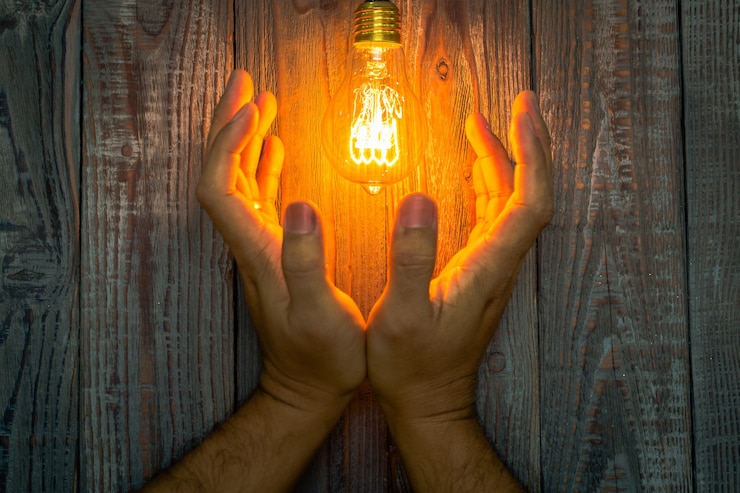 Foto gratuito le mani accanto a una lampadina accesa