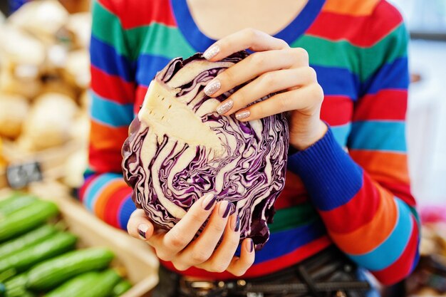 Le mani con la manicure di una ragazza indossano un maglione colorato che buca il cavolo