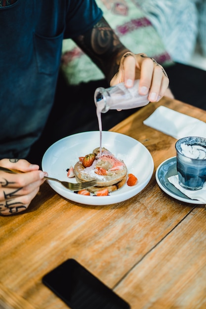 Le mani dell&#39;uomo versano la salsa dolce sui pancake