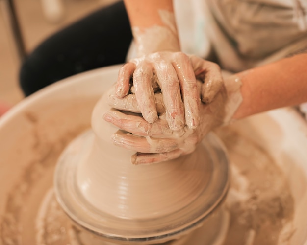 Le mani della donna in corso di fabbricazione dell&#39;argilla lanciano sulla ruota delle terraglie