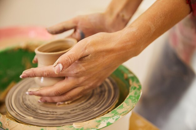 Le mani della donna stanno modellando un vaso su un cerchio