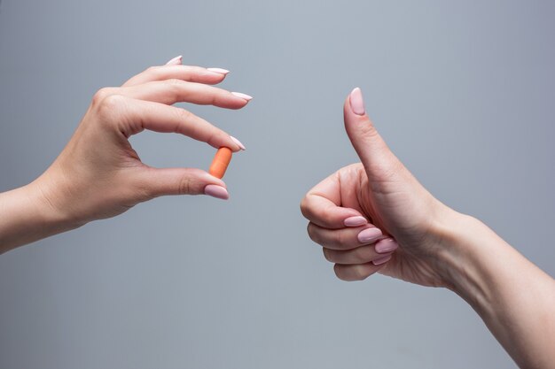 Le mani femminili che tengono il primo piano della capsula della pillola.