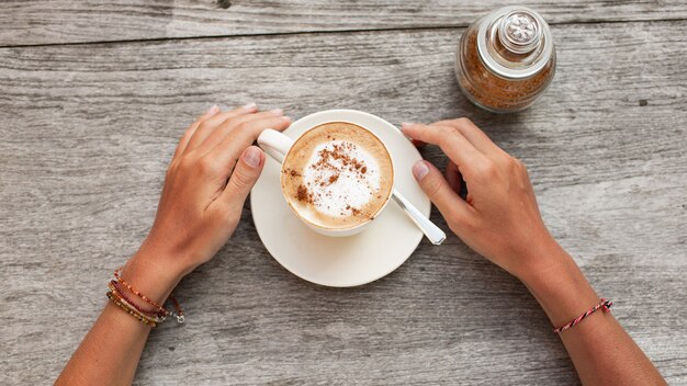 le mani tengono una tazza di caffè.