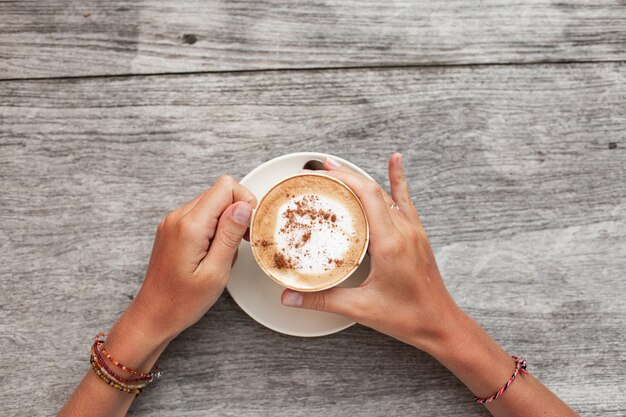 le mani tengono una tazza di caffè.