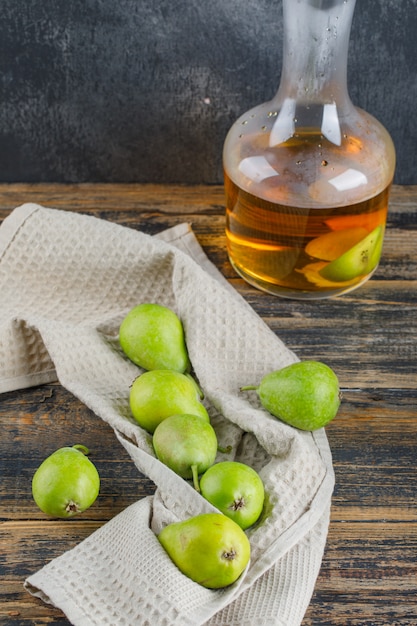 Le pere con il sidro bevono su un asciugamano di cucina sulla parete di legno e grungy