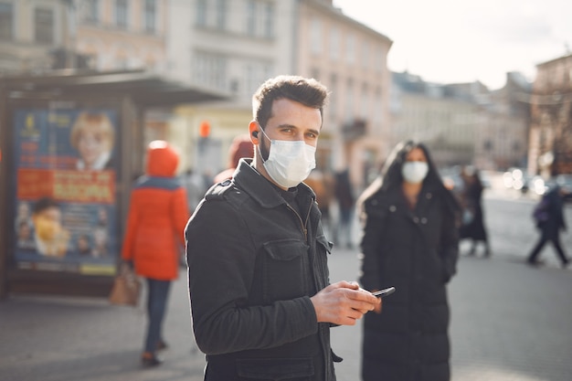 Le persone che indossano una maschera protettiva in piedi sulla strada