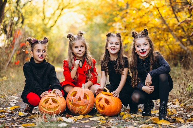 Le ragazze dei bambini si sono vestite in costumi di Halloween all'aperto con le zucche