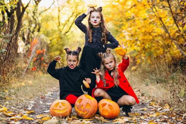 Le ragazze dei bambini si sono vestite in costumi di Halloween all'aperto con le zucche