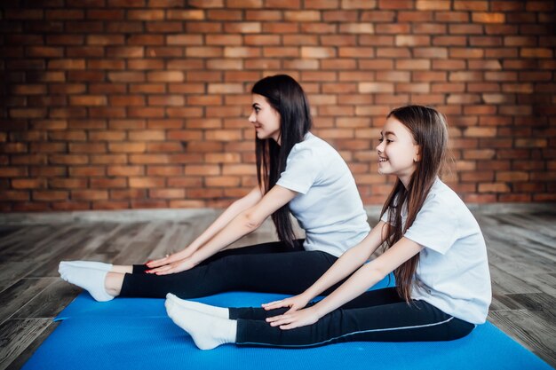 Le ragazze fanno yoga al chiuso. Madre e figlia che fanno ginnastica e stretching al centro yoga.