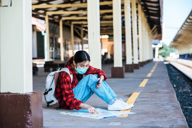 Le turisti donne si siedono e guardano la mappa sul sentiero accanto alla ferrovia.