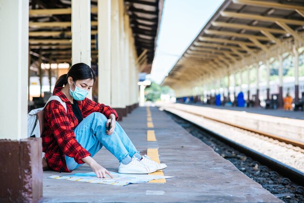 Le turisti donne si siedono e guardano la mappa sul sentiero accanto alla ferrovia.