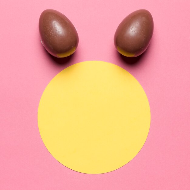 Le uova di Pasqua come l&#39;orecchio del coniglio sopra la cornice di carta bianca rotondo su sfondo rosa