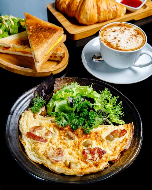 Le uova fritte con i funghi sono servito con i panini e la tazza di caffè di verdi