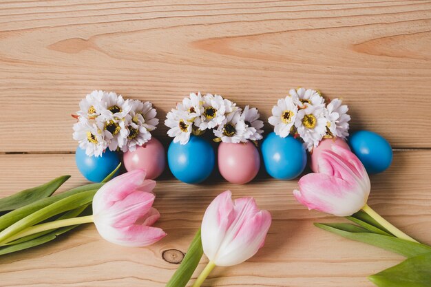 Le uova si avvicinano ai tulipani e ai fiori bianchi