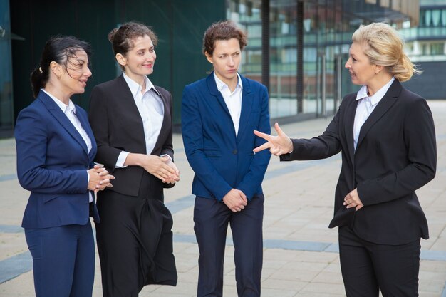 Leader aziendale che istruisce e ispira la squadra femminile. Donne di affari che indossano abiti che si incontrano e parlano in città. Leadership e concetto di lavoro di squadra