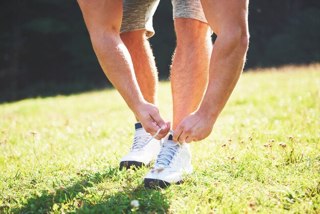 Legare scarpa sportiva. Un giovane sportivo si prepara per l'allenamento atletico e fitness all'aperto.