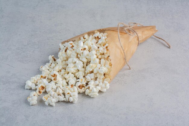 Legato avvolgimento di carta riempito di popcorn sulla superficie di marmo
