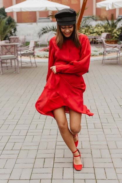 Leggy donna dai capelli castani che balla allegramente sulla terrazza del ristorante. Modello con ottimo stile divertendosi per nuove istantanee