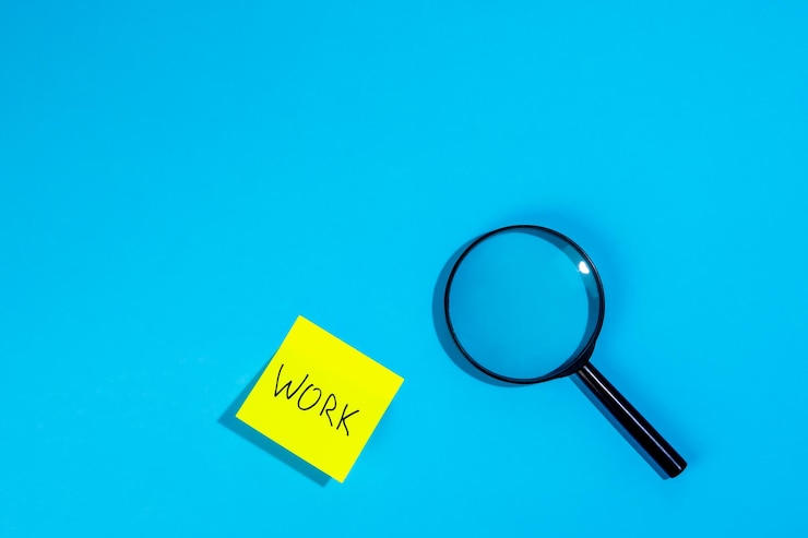 Foto gratuito lente d'ingrandimento e un adesivo con la parola lavoro su sfondo blu