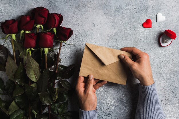 Lettera di amore della busta della tenuta della mano dell&#39;uomo di giorno di biglietti di S. Valentino con la cartolina d&#39;auguri