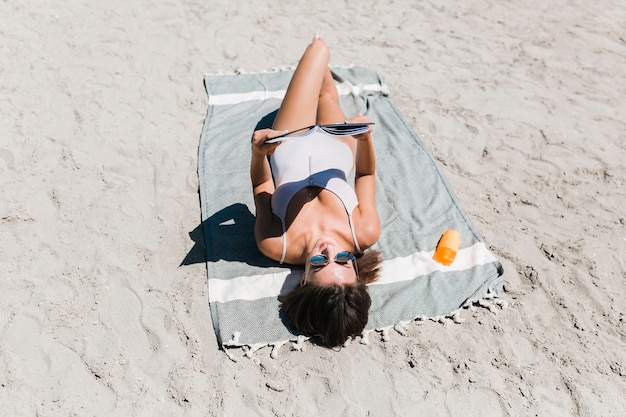 Lettura della giovane donna sulla spiaggia sabbiosa