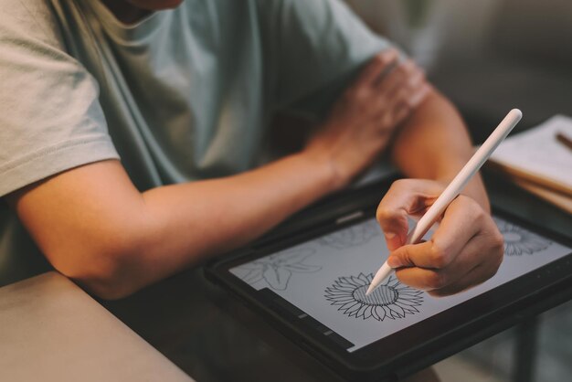 Libero professionista grafico donna asiatica che fa lavoro straordinario di notte utilizzando tablet per disegnare opere d'arte dal concetto di casa