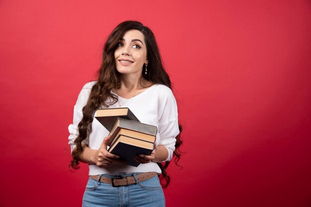 Libri della holding di modello della giovane donna su una priorità bassa rossa. Foto di alta qualità