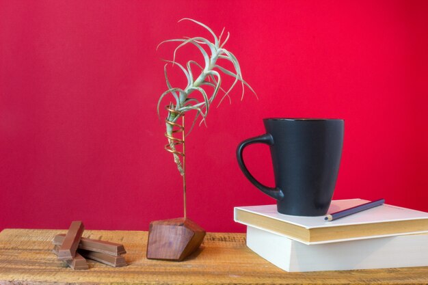 Libro con tazza di tè, cofanetto e pianta su sfondo di legno