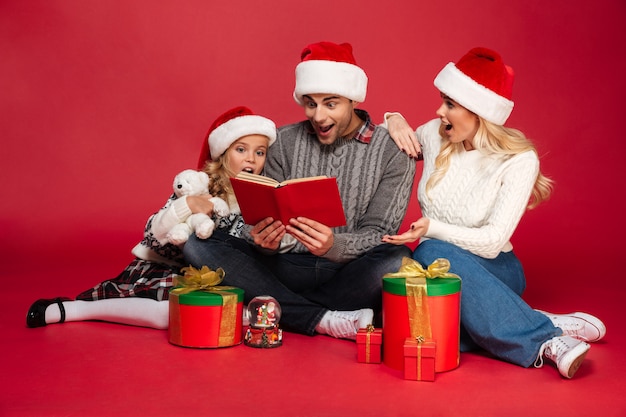 Libro di lettura da portare colpito dei cappelli di natale della giovane famiglia allegra.