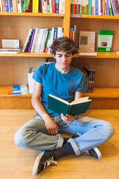 Libro di lettura dell&#39;adolescente sul pavimento delle biblioteche