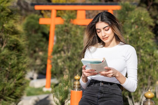 Libro di lettura della giovane bella ragazza al parco Foto di alta qualità