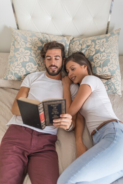 Libro di lettura delle coppie sul letto insieme