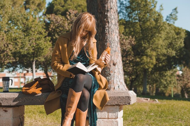 Libro di lettura donna e mangiare croissant