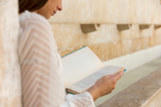 Libro di lettura femminile vicino alla costruzione di pietra