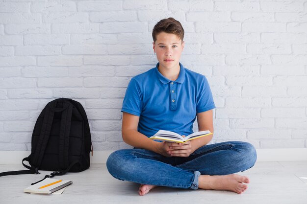 Libro di lettura ragazzo serio sul pavimento